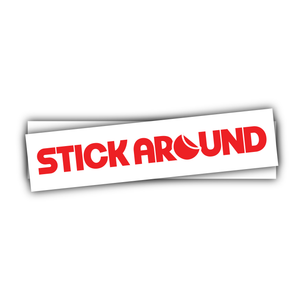 A white rectangular bumper sticker features red text that reads "STICK AROUND". The custom vinyl bumper sticker, crafted by our design team, has a subtle shadow effect below it, giving a slight three-dimensional appearance. The background is plain white.